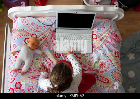 Kleines Mädchen im Bett sitzen und spielen Online-Spiele in ihrem Schlafzimmer. Erhöhte Ansicht Stockfoto