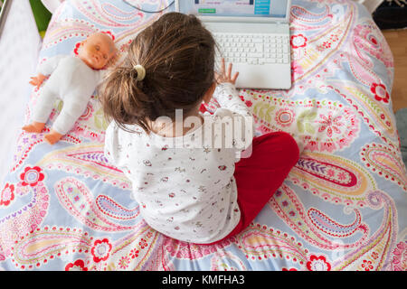 Kleines Mädchen im Bett sitzen und spielen Online-Spiele in ihrem Schlafzimmer. Erhöhte Ansicht Stockfoto