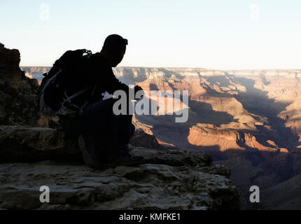 Silhouette der Mann sitzt auf den South Rim des Grand Canyon aus der Ansicht Stockfoto