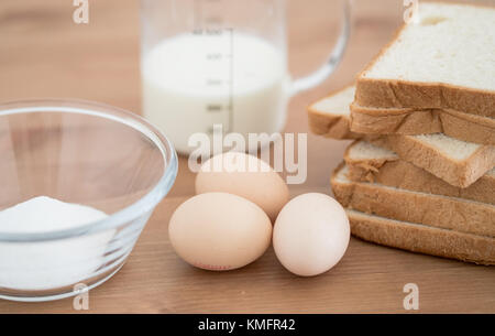 Alle Bestandteile von French Toast Rezept - Eier, Milch, Brot und Zucker auf hölzernen Hintergrund Stockfoto