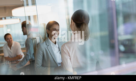 Lächelnde Unternehmerinnen im Gespräch im Büro Stockfoto