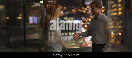 Geschäftsmann und Geschäftsfrau Handshake im Büro in der Nacht Stockfoto