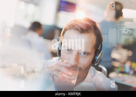 Geschäftsmann mit Kopfhörern Trinkwasser im Büro Stockfoto