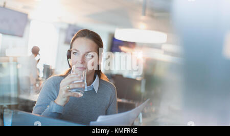 Geschäftsfrau das Headset Trinkwasser im Büro Stockfoto