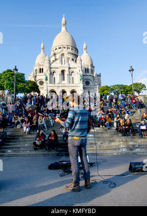 Paris, Frankreich. Montmartre. Auf den Stufen hinauf zur Sacre Coeur spielt ein Straßenmusiker vor Menschenmengen Stockfoto