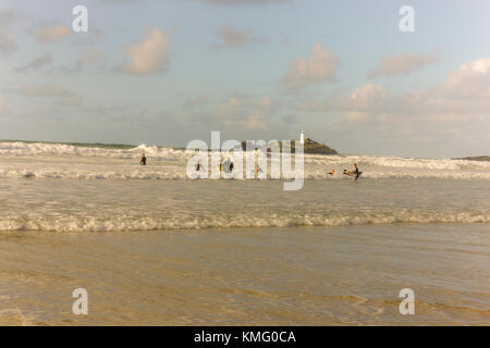 Surfer auf godrevy Beach, Cornwall South East England, mit dem godvrey Leuchtturm im Hintergrund. Stockfoto