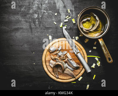 Gesalzene Heringe, mit Gewürzen und Kräutern. Schwarze Schiefertafel. Stockfoto