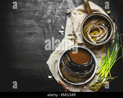 Filet von der Rollmops mit Gewürzen in einen Topf geben. Schwarze Schiefertafel. Stockfoto
