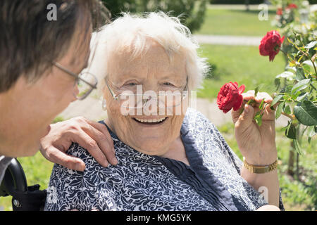 Sohn mit Mutter duftende Rose Blume im Park Stockfoto