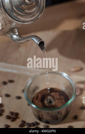 Warmes Wasser in einem Glas mit Kaffeepulver goß Stockfoto