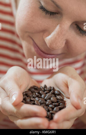 Junge Frau, die ein Geruch von gerösteten Kaffeebohnen Stockfoto