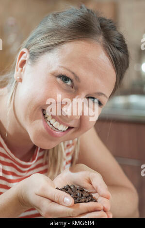 Junge Frau mit Handvoll geröstete Kaffeebohnen Stockfoto