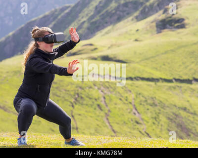 Frau übt Tai Chi-Bewegungen mit einer Brille für die virtuelle Realität Berg Stockfoto