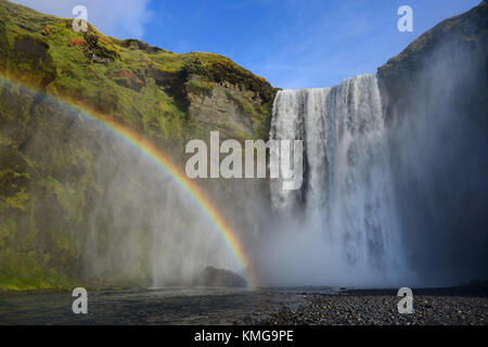 Skogafoss ist die beliebteste Wasserfall in Island. Landschaft bei Sonnenuntergang mit riesigen Regenbogen im Wassernebel. Stockfoto