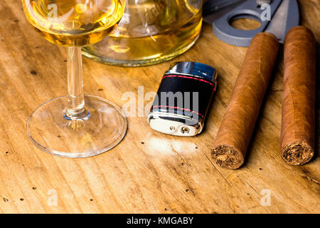 Zigarre mit Flasche und Whiskey Glas, leichter und Zigarrenabschneider auf einem alten Holz- Board Stockfoto