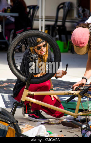 Mädchen geholfen durch junge, Rad reparieren, BMX-Fahrer bei Skate Park, während Freestyle Wettbewerb, Fuengirola, Spanien. Stockfoto