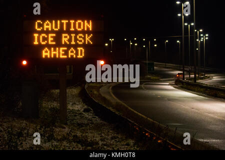 A55 neon Schild in der Nacht anzeigen Warnschild für die Autofahrer Vorsicht Eis Gefahr Vor als Sturm Caroline beginnt der Bereich mit Schnee und Frost, Halkyn, Flintshire, Wales, Vereinigtes Königreich, Stockfoto