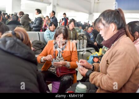 (171209) -- URUMQI, 9. Dezember 2017 (Xinhua) -- Passagiere spielen Karten am Bahnhof Kashgar in der autonomen Region Xinjiang Uygur im Nordwesten Chinas, 23. November 2017. Die 485 km lange Eisenbahnstrecke verbindet die beiden großen Oasenstädte Kashgar und Hotan, führt durch einige der abgelegensten Gegenden in Xinjiang und hat das Leben in der Wüste seit ihrem Start im Jahr 2011 verändert. Es ist die erste und einzige Eisenbahnstrecke in Hotan, über die die unterentwickelte Präfektur mit dem restlichen Eisenbahnnetz des Landes verbunden ist, das über 22.000 km Hochgeschwindigkeitsstrecken verfügt. Schlechte Verkehrsinfrastruktur hat C verursacht Stockfoto