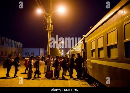 (171209) -- URUMQI, 9. Dezember 2017 (Xinhua) -- Passagiere steigen in den Zug Nr. 5809, der Kashgar und Hotan am Bahnhof Kashgar verbindet, nordwestchinesische Autonome Region Xinjiang Uygur, 24. November 2017. Die 485 km lange Eisenbahnstrecke verbindet die beiden großen Oasenstädte Kashgar und Hotan, führt durch einige der abgelegensten Gegenden in Xinjiang und hat das Leben in der Wüste seit ihrem Start im Jahr 2011 verändert. Es ist die erste und einzige Eisenbahnstrecke in Hotan, über die die unterentwickelte Präfektur mit dem restlichen Eisenbahnnetz des Landes verbunden ist, das über 22.000 km Hochgeschwindigkeitsstrecken verfügt. Schlechte Transpo Stockfoto