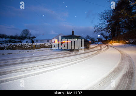 Flintshire, North Wales, UK, Dezember 2017 Wetter. Arctic chill und einem gelben Met Office Warnung für Schnee in Flintshire für Heute und Morgen eine gelbe Warnleuchte für starke Ansammlungen von Schnee. Ein Fahrer der Bewältigung der über Nacht Schnee in einem 4x4 heute Morgen im Dorf Lixwm mit ein gelbes Warnsymbol für Schnee in den nächsten 24 Std. bis zu dem, was bereits gefallen ist. Stockfoto