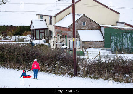 Flintshire, North Wales, UK, Dezember 2017 Wetter. Arctic chill und Met Office, der die gelbe Warnlampe für Flintshire für starke Ansammlungen von Schnee in Flintshire als Menschen den Hügel nach als Tag der Rodeln im Dorf Rhes-y-Cae, Flintshire verlassen Stockfoto