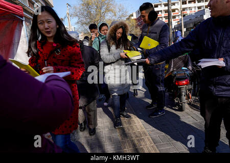 Peking, China. 10 Dez, 2017. Mitarbeiter von Nachhilfe center Anleitung Materialien an Prüflingen, die gerade die nationalen Beamten Prüfung in Peking, Hauptstadt von China, 10.12.2017. Mehr als 1,1 Millionen Menschen nahmen die nationalen öffentlichen Diener Prüfung in China Sonntag, ein Sprung vom letzten Jahr 984,000, Kennzeichnung, das zweite Mal die Anzahl der Millionengrenze geschlagen hat. Credit: Shen Bohan/Xinhua/Alamy leben Nachrichten Stockfoto