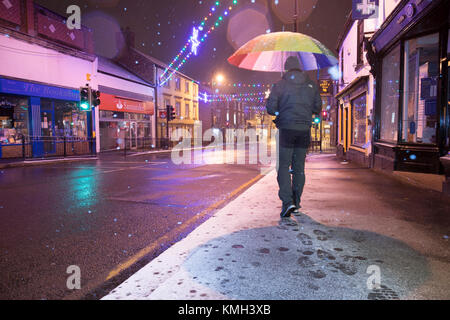 Flintshire, North Wales, UK, Dezember 2017 Wetter Sturm Caroline. Eine Met Office, der die gelbe Warnlampe für Schnee und schwere Störungen haben für viele zentrale Teile von England ausgestellt worden und die meisten von Wales. Schnee beginnt in der Stadt von Schimmel, Flintshire zu fallen, als eine Person, die Köpfe, die in den Schnee Stockfoto