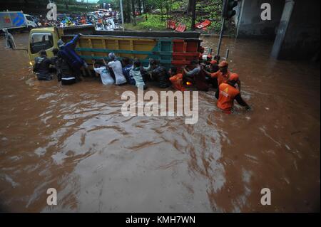 (171211) -- JAKARTA, Dez. 11, 2017 (Xinhua) - Mitglieder der öffentlichen Einrichtung Maintenance Agency (PPSU) und die Einheimischen, die versuchen, ein Fahrzeug in einem Überflutete Straße in Jakarta, Indonesien, Dec, 11 fest zu drücken. 2017. Heavy Rain von mehreren Stunden links waterlogged Straßen und verursacht Staus in einigen Bereichen von Jakarta. (Xinhua / Zulkarnain) (zjl) Stockfoto