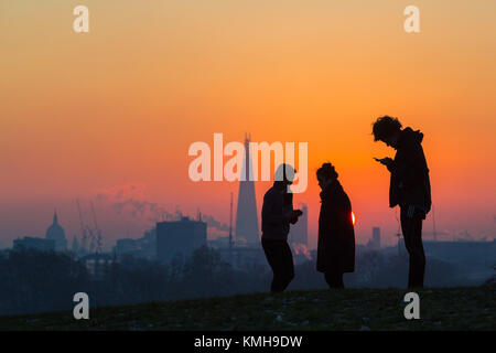 London, Großbritannien. 12 Dez, 2017. London, 12. Dezember 2017. Am frühen Morgen Wanderer in Silhouette gegen die Skyline der Stadt wie die Sonne an einem klaren sehr kalten Morgen in London, von Primrose Hill in Camden gesehen. Credit: Paul Davey/Alamy leben Nachrichten Stockfoto