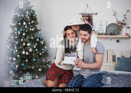 Glückliche Familie an Weihnachten Morgen Eröffnung gaben zusammen in der Nähe der Tanne. Das Konzept der Familie Glück und Wohlergehen. Stockfoto