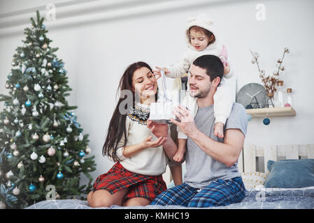 Glückliche Familie an Weihnachten Morgen Eröffnung gaben zusammen in der Nähe der Tanne. Das Konzept der Familie Glück und Wohlergehen. Stockfoto