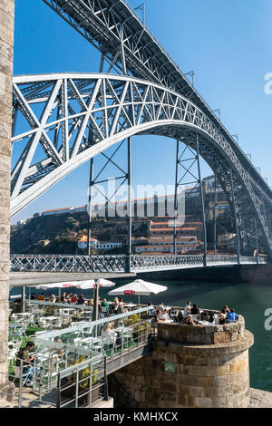 Cafe Bar auf der Cais da Ribeira, neben dem Fluss Ufer des Douro in der Ribeira Viertel von Porto, Portugal. Mit dem Dom Luis I Brücke in backgrou Stockfoto