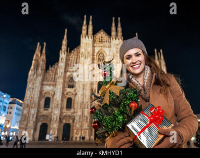 Lustige Weihnachten Reise nach Mailand, Italien. Porträt von lächelnden Frau mit Weihnachtsbaum und Geschenk in Mailand, Italien Stockfoto