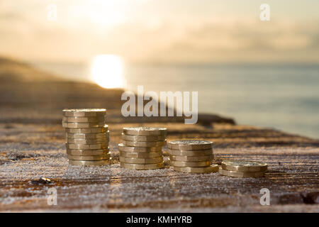 Britisches Geld, Pfund Münzen in steigenden Stacks auf sandigen Holz. Neue Pfund in einer warmen Sunrise Licht. Stockfoto
