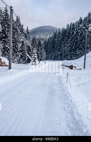 Winterlandschaft mit Schnee Straße, Wald und Hügel auf dem Hintergrund in Beskiden in der Nähe von moravka Dorf in der Tschechischen Republik Stockfoto