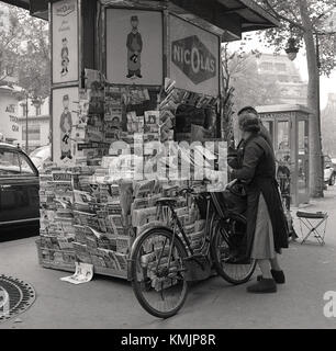 1950, historisches Bild vom Kunden an einem Kiosk im Zentrum von Paris, Frankreich mit Werbung für Nicolas, der Pariser Wine Company. Stockfoto