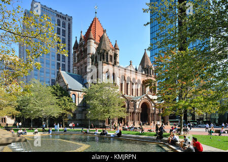 Die Trinity Church, einem nationalen historischen Wahrzeichen Gebäude in Back Bay, Boston. Leute um die Copley Square Brunnen hängend an einem sonnigen Tag der Fall. Stockfoto