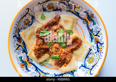 Ravioli gefüllt mit Ziegenkäse, mit Tomatensoße, Käse und frischem Grün Parmigano-Reggiano Basilikum Stockfoto