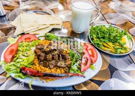 Close up detaillierte Ansicht von gegrillten leckeren Leber türkische Shish Kebab auf einem weißen Teller mit geschnittenem lavash, Petersilie, Zwiebeln, Salat, Tomaten, Grill Stockfoto