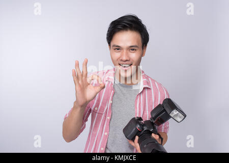 Jungen asiatischen Fotograf holding Digitalkamera, während im Studio arbeiten Stockfoto