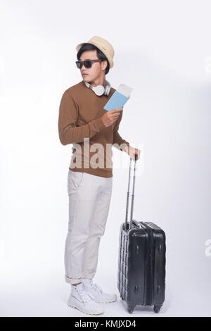 Volle Länge des jungen Touristen asiatischer Mann holding Passport mit Koffer über grauer Hintergrund Stockfoto