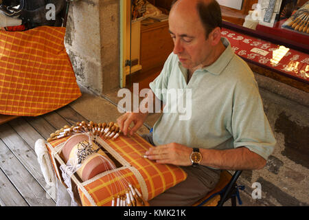 Mann mit Spulenkörper für Lace makingon Bürgersteig vor Speichern, Le Puy-en-Velay, Auvergne, Frankreich Stockfoto