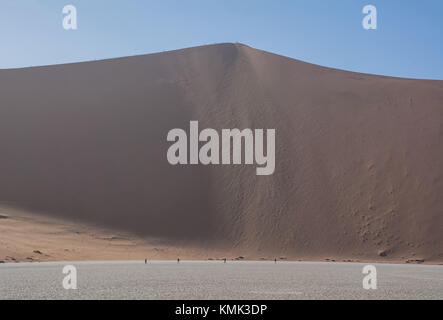 Touristen klettern einer Düne in der namibischen Wüste bei Dead Vlei Stockfoto