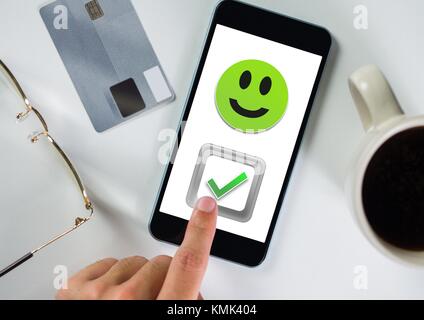 Digital composite von Hand berühren richtig ticken und Smiley auf dem Telefon Stockfoto