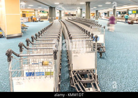 Auch Reihen von leeren Wagen für das Gepäck in den Aufbau einer modernen Flughafen, Menschen und Menschen Silhouetten auf ihr Gepäck Stockfoto