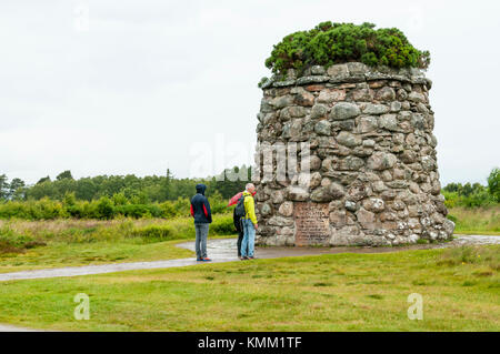 Touristen, die sich in der regen die Inspektion der Gedenkstätte errichtet im Jahre 1881 auf das Schlachtfeld von Culloden. Stockfoto