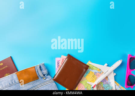 Reiseplanung Zubehör, Flugzeug, Brieftasche, Sonnenbrille, Geld, Notizen, jeans, Action Kamera, Weltkarte und Reisepass mit Leerzeichen auf Blau hinterg Stockfoto