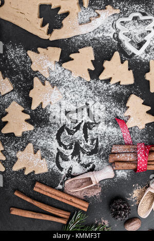 Rahmen der Backzutaten und Mautgebühren für Lebkuchen. Cookies und Gewürze über rustikale Tisch mit Weihnachtsbaum auf Mehl von oben betrachtet lackiert Stockfoto