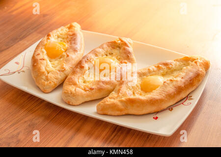 Khachapuri adschariens an der Platte. Torte mit Mozzarella und Ei öffnen. Stockfoto