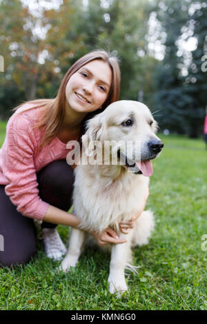 Portrait von brunette umarmen Labrador auf Rasen im Sommer Park Stockfoto